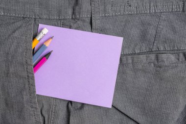 Resmi çalışma pantolonuön cebinde ekipman ve mor bir not kağıdı yazma. Erkek iş pantolonuna yerleştirilen notasyon kağıdı ile sabit kalem