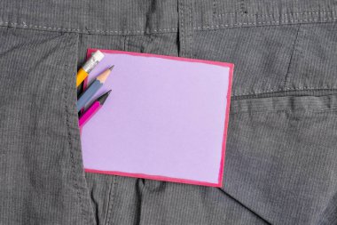 Resmi çalışma pantolonuön cebinde ekipman ve mor bir not kağıdı yazma. Erkek iş pantolonuna yerleştirilen notasyon kağıdı ile sabit kalem