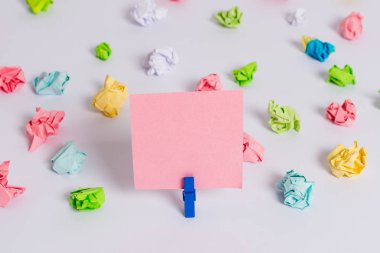 Beyaz bir zeminin ortasında boş dikdörtgen kare şeklinde hatırlatma notu etrafında yerleştirilen renkli buruşuk levhalar. Ofis malzemeleri, bir bağlantı elemanı tarafından sabitlenmiş boş kağıt.