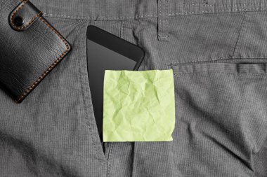 Bir cüzdan ve sarı not kağıdı ile pantolon ön cebinde Akıllı telefon cihazı. Modern gadget notasyon levha artı çanta yakın erkek pantolon içine yerleştirilir