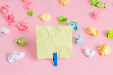 Pembe arka planda boş dikdörtgen kare şeklinde hatırlatma notu etrafında yerleştirilen renkli buruşuk levhalar. Ofis malzemeleri, bir bağlantı elemanı tarafından sabitlenmiş boş kağıt.