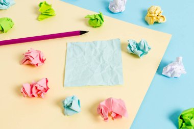 Renkli buruşuk levhalar ve boş dikdörtgen şekilli hatırlatma notu mavi bir arka plan ve sarı kare ortasında yerleştirilir. Ofis malzemeleri, bağlantı elemanı.