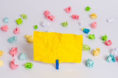 Beyaz bir zeminin ortasında boş dikdörtgen kare şeklinde hatırlatma notu etrafında yerleştirilen renkli buruşuk levhalar. Ofis malzemeleri, bir bağlantı elemanı tarafından sabitlenmiş boş kağıt.