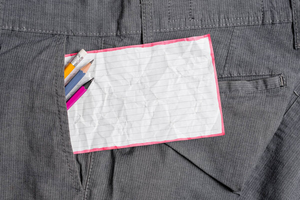 Writing equipment and a white note paper inside the formal working trousers front pocket. Stationary pencil with notation sheet placed in man work pants