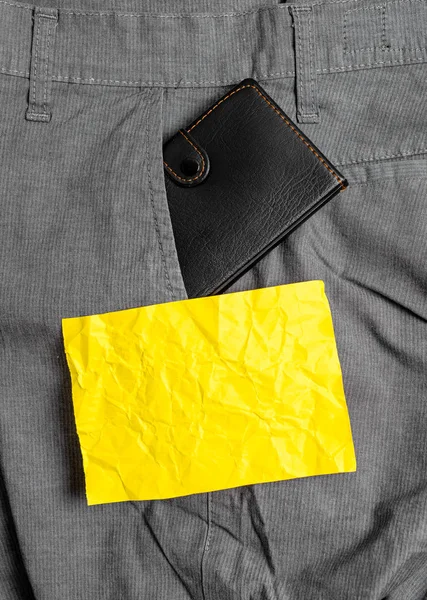 Liten plånbok i byxorna framficka bredvid gult anteckningsblad. Lilla väskan är placerad inuti man Pants nära notationsark. Konstnärligt sätt att arrangera platt Lay Photography — Stockfoto