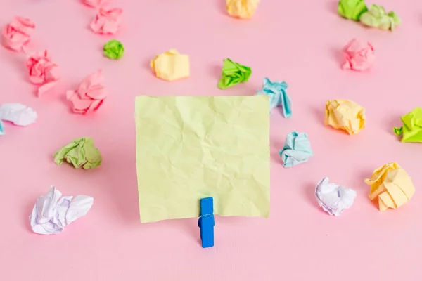 Hojas arrugadas de color colocadas alrededor del rectángulo vacío en forma cuadrada nota recordatorio en el fondo rosa. Material de oficina, papel en blanco fijado por un cierre . — Foto de Stock