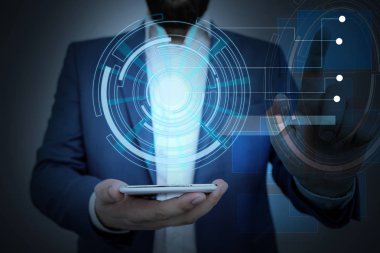 Erkek insan en son gelişmiş cihazları kullanarak sunum yapıyor. Adam, akıllı aletlerin nasıl çalıştığını gösteren resmi bir takım elbise giyiyor. Modern hayatın fotoğrafı..