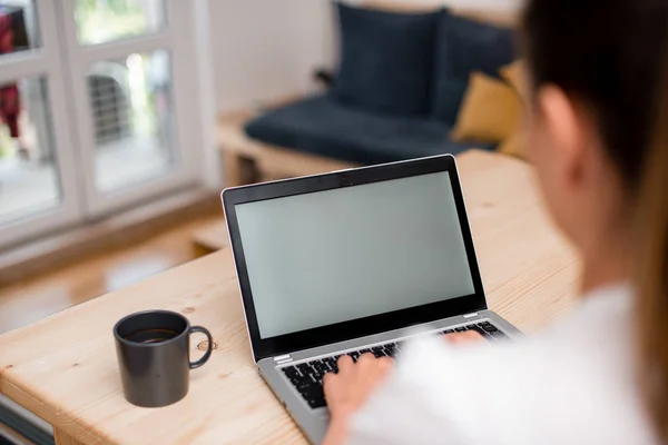 Jonge dame met behulp van een grijze laptop computer en het typen van het zwarte toetsenbord met beide handen in een kamer. Vrouw in een huis ambient met kantoorbenodigdheden en technologische apparaten. — Stockfoto