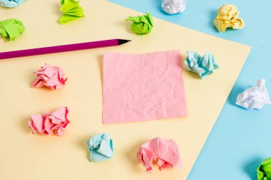 Renkli buruşuk levhalar ve boş dikdörtgen şekilli hatırlatma notu mavi bir arka plan ve sarı kare ortasında yerleştirilir. Ofis malzemeleri, bağlantı elemanı.