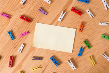 Renkli clothespin ahşap bir zemin ortasında boş bir dikdörtgen kare şeklinde hatırlatma notu etrafında yayıldı. Oluklar ve yuvaları ile ahşap. Ofis malzemeleri.