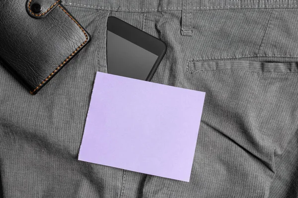 Smartphone-enhet i byxorna framficka med plånbok och lila anteckningspapper. Modern gadget är placerad inuti man Pants nära notation Sheet plus handväska — Stockfoto
