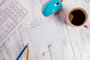 Beyaz ahşap zemin, bilgisayar klavyesi ve fare üzerinde kare dikdörtgen boş kağıt nota. Hatırlatıcının etrafında kahve ve kalem ler var. Ofis malzemeleri, boş alan.