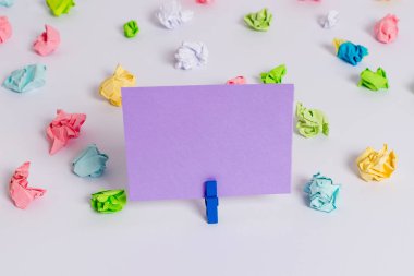 Beyaz bir zeminin ortasında boş dikdörtgen kare şeklinde hatırlatma notu etrafında yerleştirilen renkli buruşuk levhalar. Ofis malzemeleri, bir bağlantı elemanı tarafından sabitlenmiş boş kağıt.