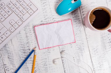 Beyaz ahşap zemin, bilgisayar klavyesi ve fare üzerinde kare dikdörtgen boş kağıt nota. Hatırlatıcının etrafında kahve ve kalem ler var. Ofis malzemeleri, boş alan.