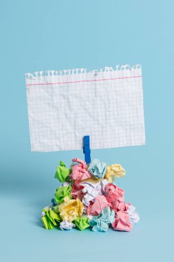 Mavi bir çamaşır iğnesi ile sabitlenmiş buruşuk kağıtları bir yığın yukarıda Kare şeklinde hatırlatma. Boş renkli bir notun altına yığılmış farklı yapraklar. Açık mavi arka plan.