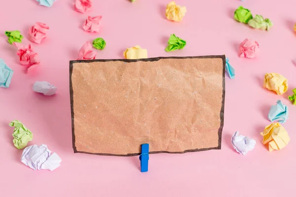 Folhas de crumpled coloridas colocadas em torno da nota de lembrete em forma quadrada retangular vazia no fundo rosa. Material de escritório, papel em branco fixado por um fixador . — Fotografia de Stock