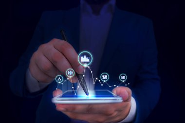 Erkek insan en son gelişmiş cihazları kullanarak sunum yapıyor. Adam, akıllı aletlerin nasıl çalıştığını gösteren resmi bir takım elbise giyiyor. Modern hayatın fotoğrafı..