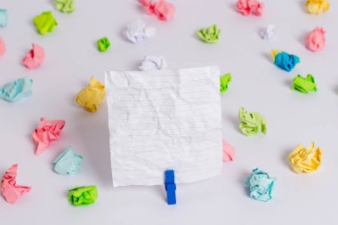 Beyaz bir zeminin ortasında boş dikdörtgen kare şeklinde hatırlatma notu etrafında yerleştirilen renkli buruşuk levhalar. Ofis malzemeleri, bir bağlantı elemanı tarafından sabitlenmiş boş kağıt.