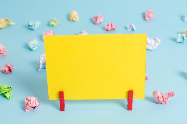 Renkli buruşturulmuş kağıtlar ve mavi bir arka plan dikdörtgen kare şeklinde renkli not. Boş bir alana bir hatırlatma kağıdı asan kırmızı klip. Işık ofis tablosu.