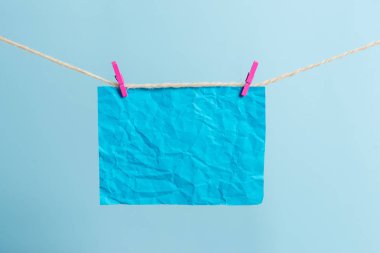 Dikdörtgen şeklinde not renkli kağıt beyaz ahşap arka planda clothespin tarafından bir çamaşır ipi kırpılmış. Kare boş hatırlatma ve ofis ekipmanları malzemeleri hafif ahşap bir masada.