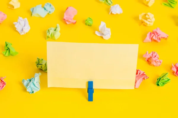 Hojas arrugadas de color colocadas alrededor del rectángulo vacío en forma cuadrada nota recordatorio en el fondo amarillo. Material de oficina, papel en blanco fijado por un cierre. — Foto de Stock