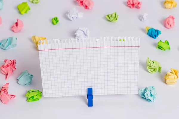 Hojas arrugadas de color colocadas alrededor del rectángulo vacío en forma cuadrada nota recordatorio en el centro de un piso blanco. Material de oficina, papel en blanco fijado por un cierre . — Foto de Stock