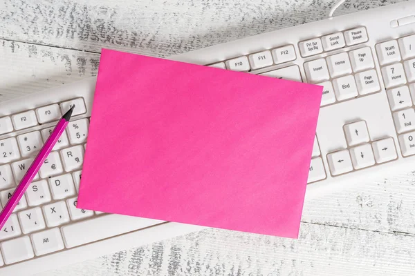 Rektangel formad anteckning färgat papper i ett tangentbord och en vit trä bakgrund. Fyrkantig tom påminnelse och kontorsutrustning levererar i ett ljust trä skrivbord. — Stockfoto
