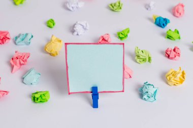 Beyaz bir zeminin ortasında boş dikdörtgen kare şeklinde hatırlatma notu etrafında yerleştirilen renkli buruşuk levhalar. Ofis malzemeleri, bir bağlantı elemanı tarafından sabitlenmiş boş kağıt.