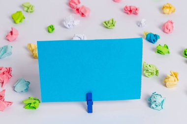 Beyaz bir zeminin ortasında boş dikdörtgen kare şeklinde hatırlatma notu etrafında yerleştirilen renkli buruşuk levhalar. Ofis malzemeleri, bir bağlantı elemanı tarafından sabitlenmiş boş kağıt.