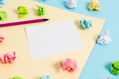 Renkli buruşuk levhalar ve boş dikdörtgen şekilli hatırlatma notu mavi bir arka plan ve sarı kare ortasında yerleştirilir. Ofis malzemeleri, bağlantı elemanı.