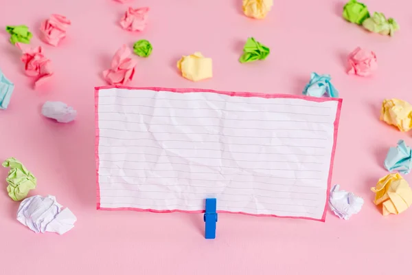 Feuilles froissées colorées placées autour de la note de rappel rectangulaire vide en forme de carré dans le fond rose. Fournitures de bureau, papier blanc épinglé par une attache . — Photo