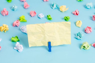 Mavi arka planda boş dikdörtgen kare şeklinde hatırlatma notu etrafında yerleştirilen renkli buruşuk levhalar. Ofis malzemeleri, bir bağlantı elemanı tarafından sabitlenmiş boş kağıt.
