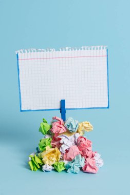 Mavi bir çamaşır iğnesi ile sabitlenmiş buruşuk kağıtları bir yığın yukarıda Kare şeklinde hatırlatma. Boş renkli bir notun altına yığılmış farklı yapraklar. Açık mavi arka plan.
