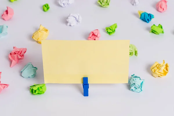 Hojas arrugadas de color colocadas alrededor del rectángulo vacío en forma cuadrada nota recordatorio en el centro de un piso blanco. Material de oficina, papel en blanco fijado por un cierre . — Foto de Stock