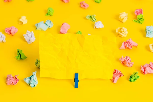 Folhas de crumpled coloridas colocadas em torno da nota de lembrete em forma quadrada retangular vazia no fundo amarelo. Material de escritório, papel em branco fixado por um fixador. — Fotografia de Stock