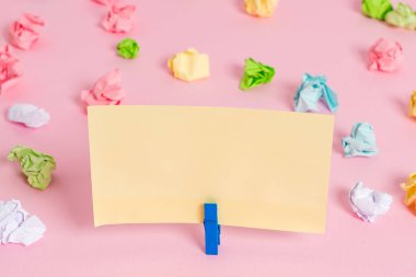 Pembe arka planda boş dikdörtgen kare şeklinde hatırlatma notu etrafında yerleştirilen renkli buruşuk levhalar. Ofis malzemeleri, bir bağlantı elemanı tarafından sabitlenmiş boş kağıt.