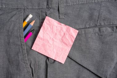 Resmi çalışma pantolonu ön cebinde ekipman ve pembe bir not kağıt yazma. Erkek iş pantolonuna yerleştirilen notasyon kağıdı ile sabit kalem