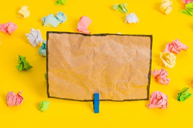 Sarı arkaplandaki boş dikdörtgen kare şekilli hatırlatma notunun etrafına yerleştirilmiş renkli buruşuk çarşaflar. Ofis malzemeleri, boş kağıtlar..