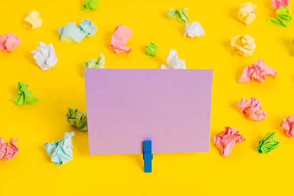 Hojas arrugadas de color colocadas alrededor del rectángulo vacío en forma cuadrada nota recordatorio en el fondo amarillo. Material de oficina, papel en blanco fijado por un cierre. — Foto de Stock