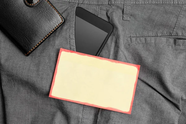 Smartphone-enhet i byxorna frontficka med en plånbok och gult anteckningspapper. Modern gadget är placerad inuti man Pants nära notation Sheet plus handväska — Stockfoto
