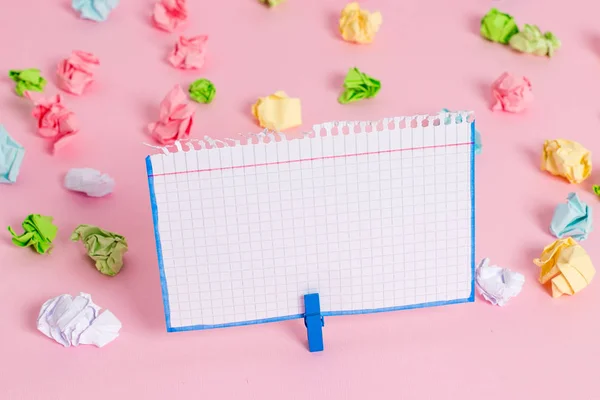 Hojas arrugadas de color colocadas alrededor del rectángulo vacío en forma cuadrada nota recordatorio en el fondo rosa. Material de oficina, papel en blanco fijado por un cierre . — Foto de Stock