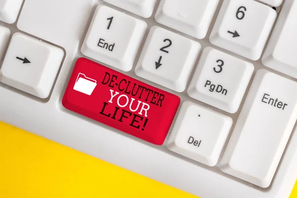 Escritura a mano conceptual que muestra De Clutter Your Life. Exhibición de fotos de negocios eliminar elementos innecesarios de lugares desordenados o hacinados Teclado blanco de PC con papel de nota sobre el fondo blanco . — Foto de Stock