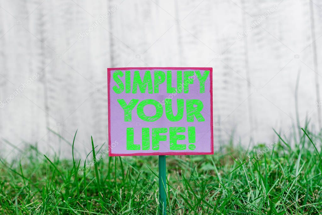 Text sign showing Simplify Your Life. Conceptual photo focused on important and let someone else worry about less ones Plain empty paper attached to a stick and placed in the green grassy land.