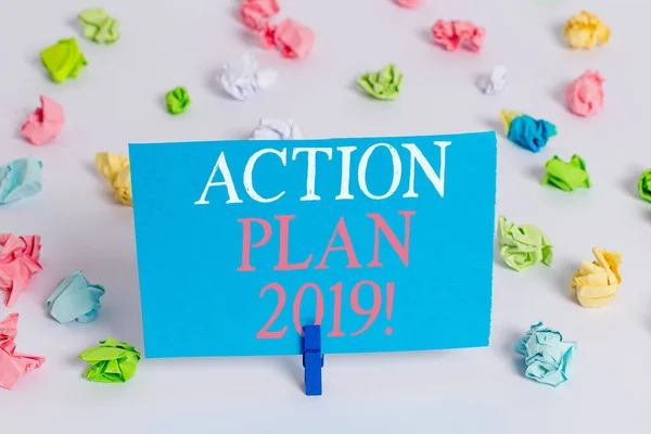 Writing note showing Action Plan 2019. Business photo showcasing proposed strategy or course of actions for current year Colored crumpled paper empty reminder white floor clothespin.