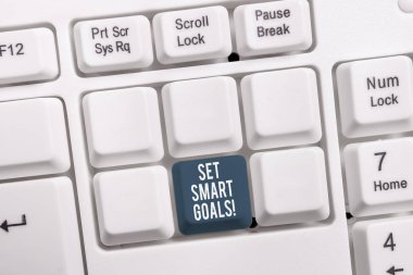 Set Smart Goals'ı gösteren kavramsal el yazısı. Fikirlerinizi netleştirmek için iş fotoğraf vitrin listesi odak çabaları beyaz arka plan üzerinde not kağıdı ile akıllıca beyaz pc klavye kullanın.