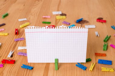 Renkli clothespin ahşap bir zemin ortasında boş bir dikdörtgen kare şeklinde hatırlatma notu etrafında yayıldı. Oluklar ve yuvaları ile ahşap. Ofis malzemeleri.