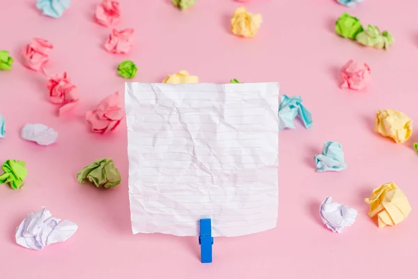 Folhas de crumpled coloridas colocadas em torno da nota de lembrete em forma quadrada retangular vazia no fundo rosa. Material de escritório, papel em branco fixado por um fixador . — Fotografia de Stock