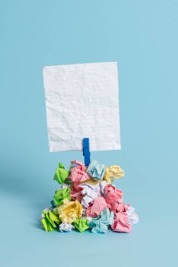 Mavi bir çamaşır iğnesi ile sabitlenmiş buruşuk kağıtları bir yığın yukarıda Kare şeklinde hatırlatma. Boş renkli bir notun altına yığılmış farklı yapraklar. Açık mavi arka plan.