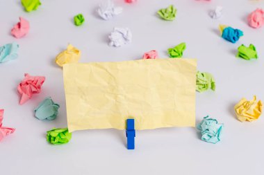 Beyaz bir zeminin ortasında boş dikdörtgen kare şeklinde hatırlatma notu etrafında yerleştirilen renkli buruşuk levhalar. Ofis malzemeleri, bir bağlantı elemanı tarafından sabitlenmiş boş kağıt.