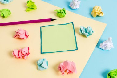 Renkli buruşuk levhalar ve boş dikdörtgen şekilli hatırlatma notu mavi bir arka plan ve sarı kare ortasında yerleştirilir. Ofis malzemeleri, bağlantı elemanı.